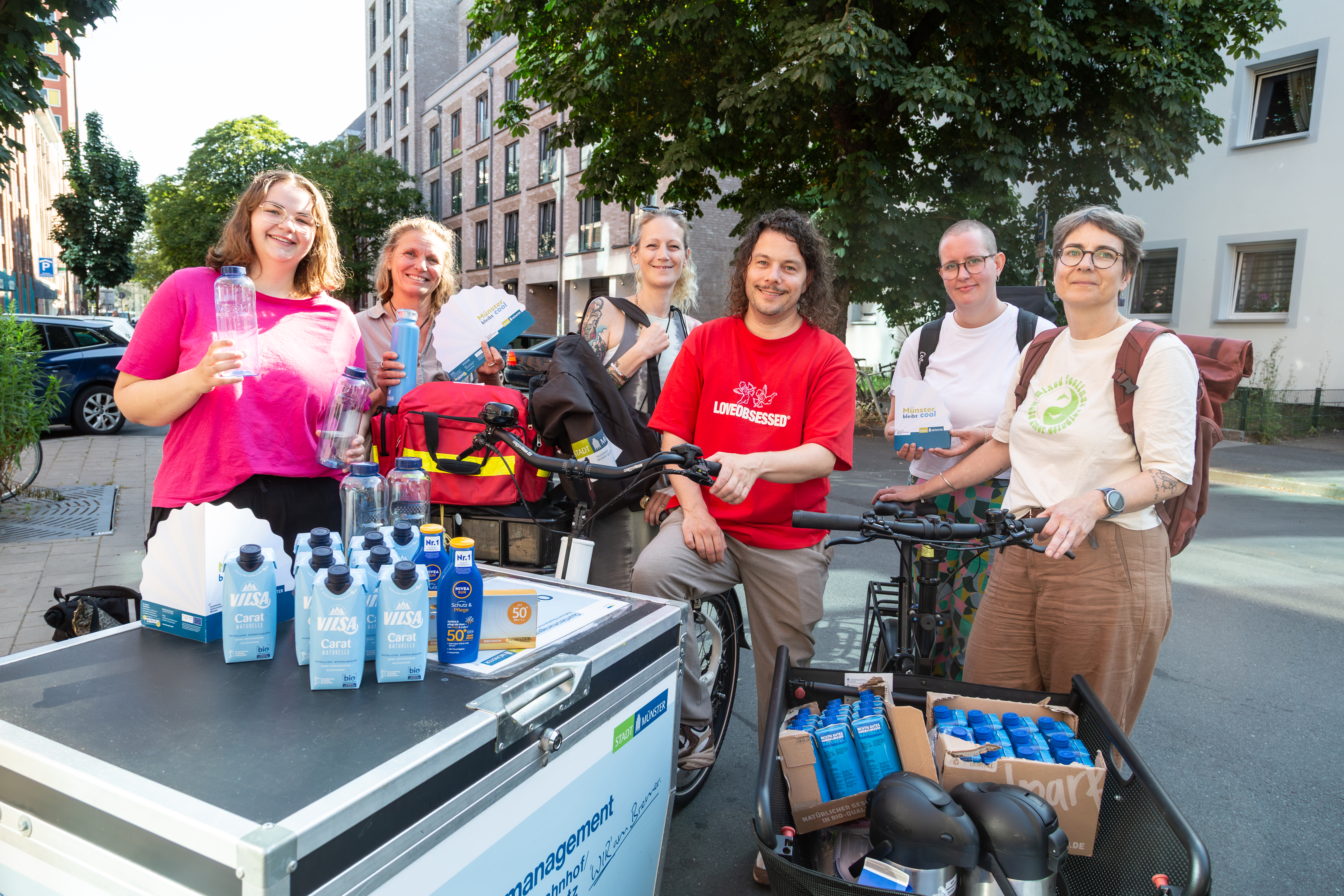 Gruppenbild mit Lastenrad Wasser in Tetrapaks und Sonnenmilch