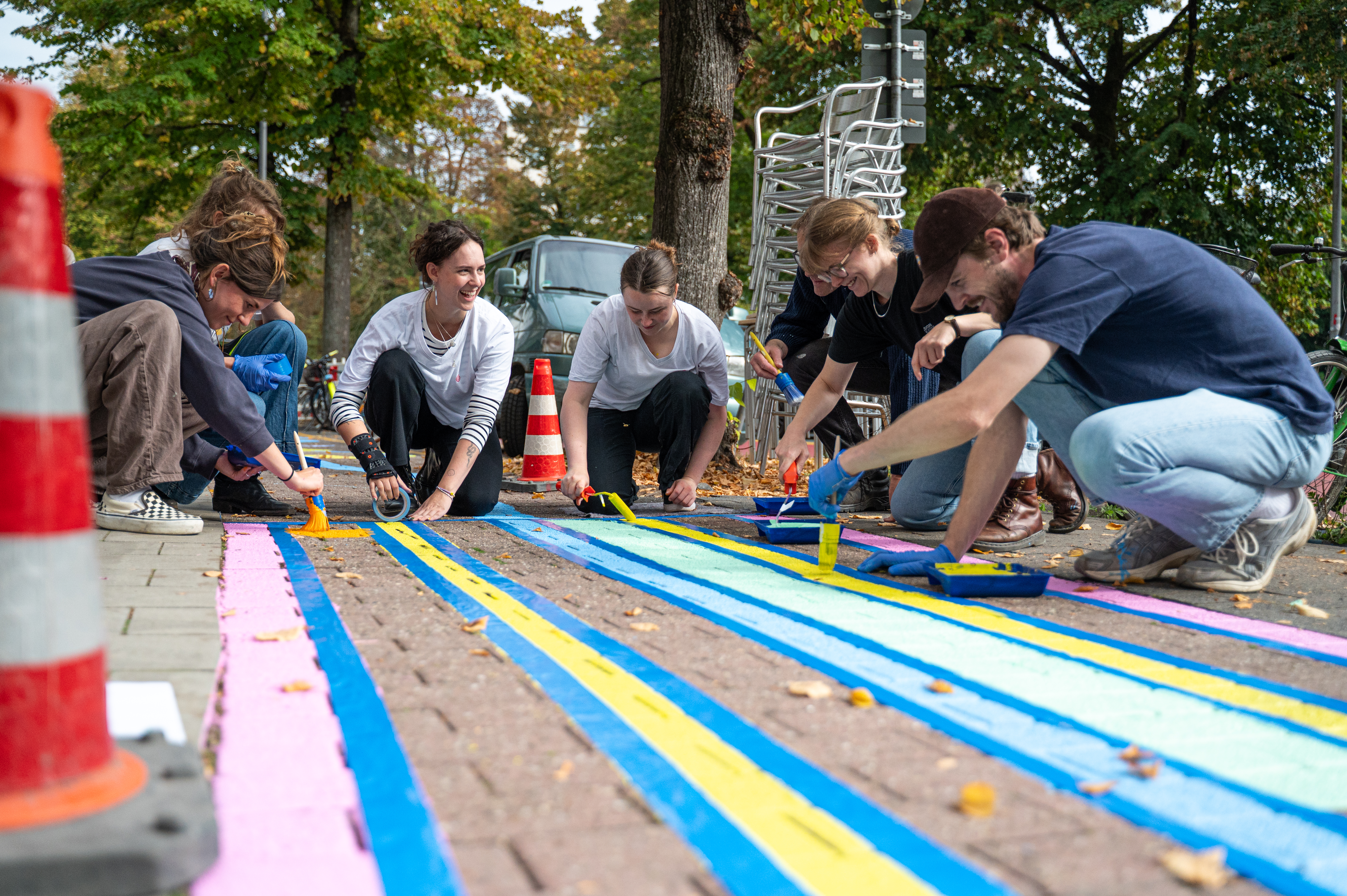 Junge Designerinnen und Designer der Münster School of Design der FH Münster übermalen das bisher rot gefärbte Pflaster mit bunten Motiven 