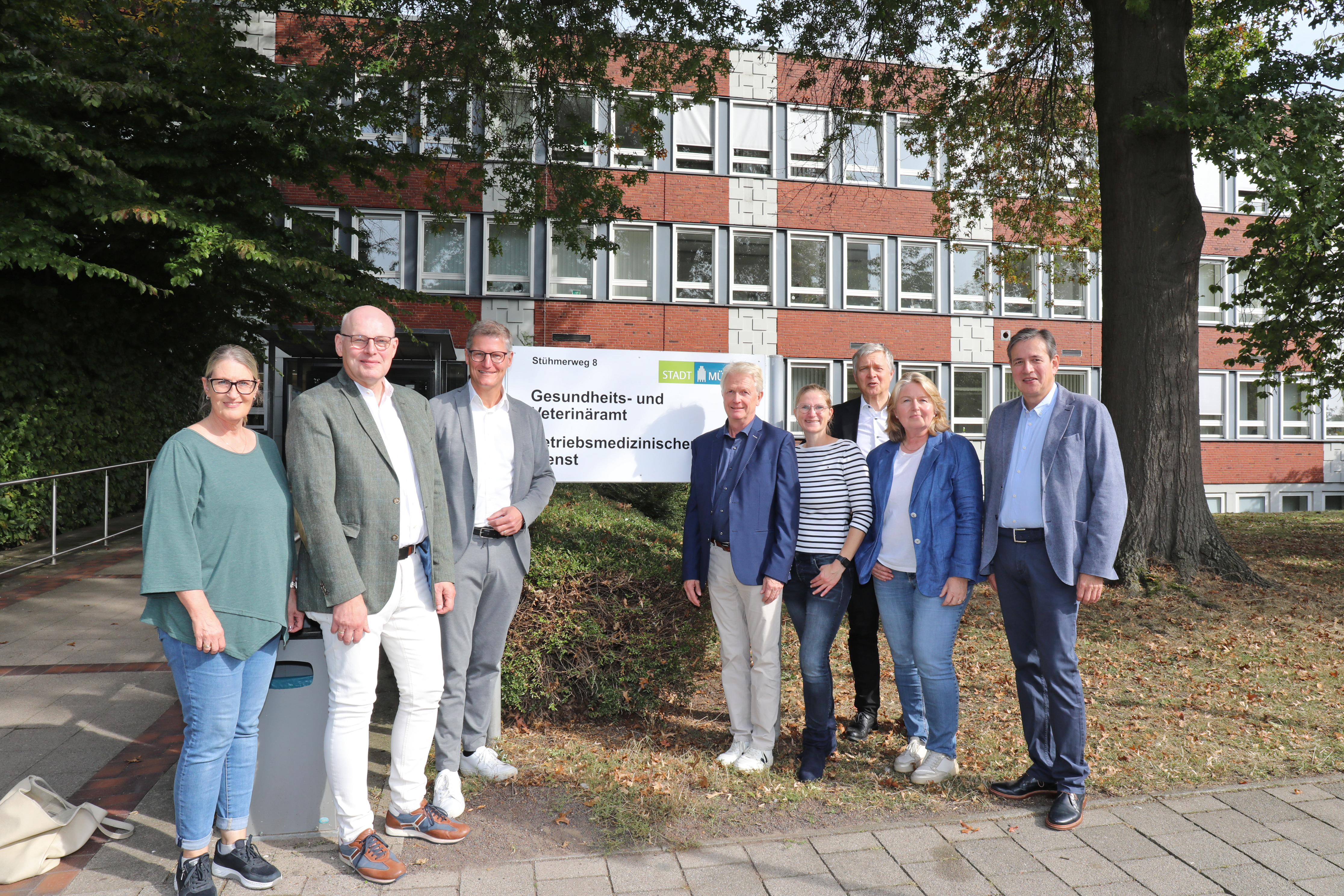 Petra Mertens (Gesundheits- und Veterinäramt), PD Dr. Michael Böswald (ÄKWL), Oberbürgermeister Tilman Fuchs, Dr. Ralf Becker (Hausärzteverbund Münster), Dr. Nike Strobelt (Kinderärztin), Dr. Markus Wenning, (ÄKWL), Andrea Bonse (stellvertretende Leiterin Gesundheits- und Veterinäramt) und Dr. Hendrik Oen (KVWL) stehen vor dem Gesundheitsamt.
