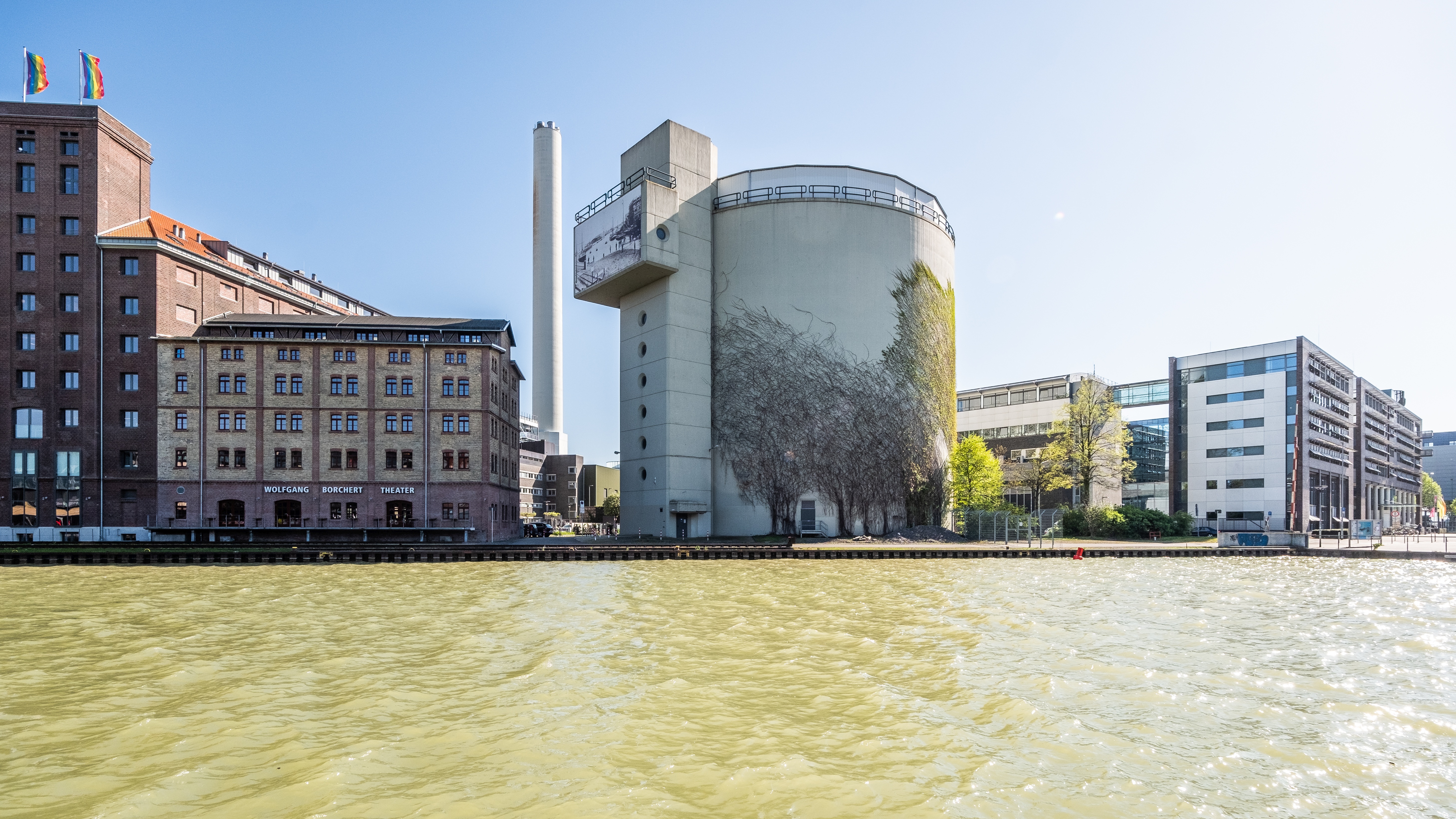 Blick über das Wasser auf einen Warmwasserspeicher in Form eines großen Betonrundbaus
