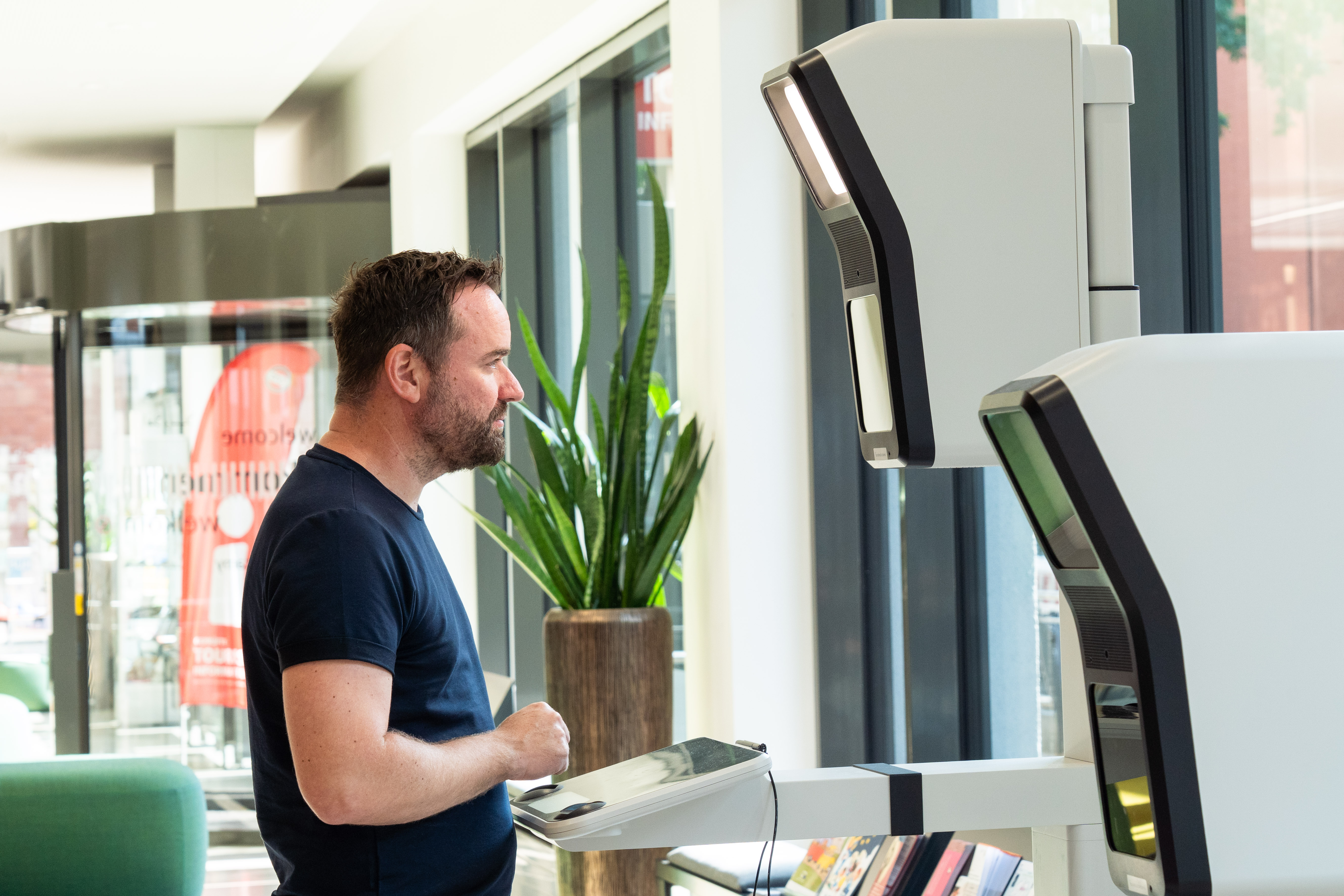 Ein Mann steht vor einem Passbild-Automaten in der Stadtverwaltung