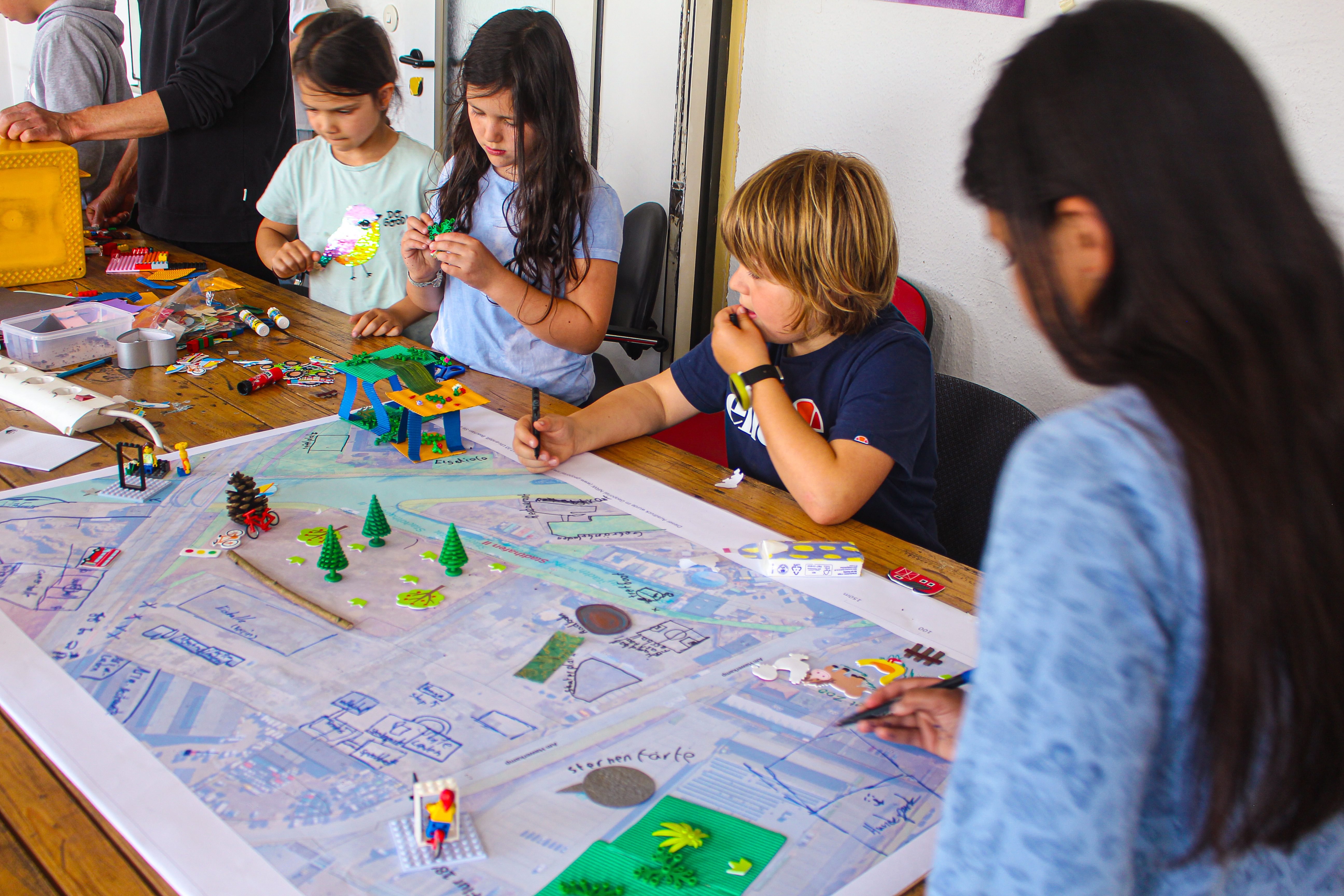 Vier Schülerinnen und Schüler stehen um einen Tisch und bearbeiten eine Karte