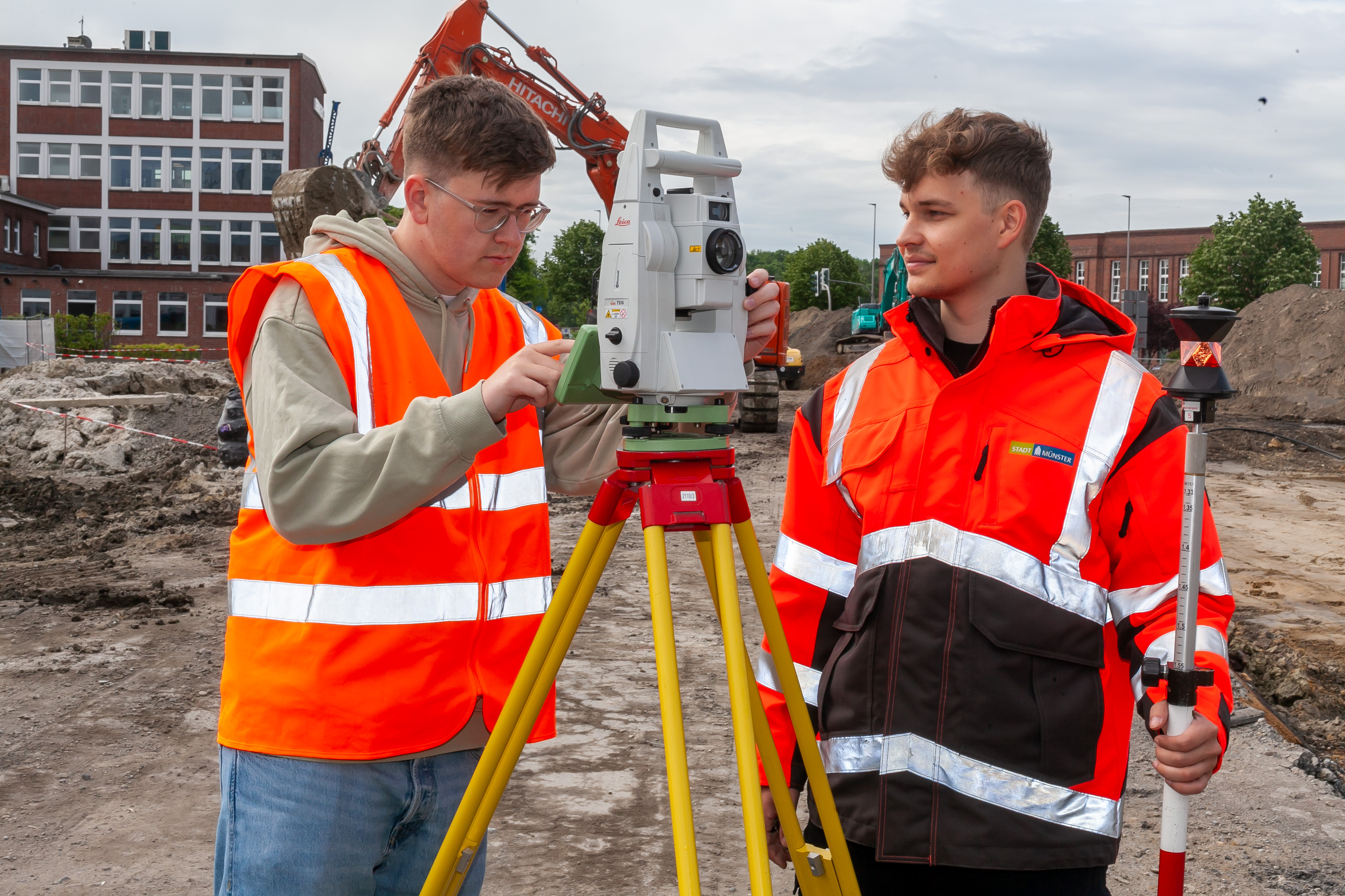 Zwei Junge Männer auf einer Baustelle mit einem Vermessungsgerät