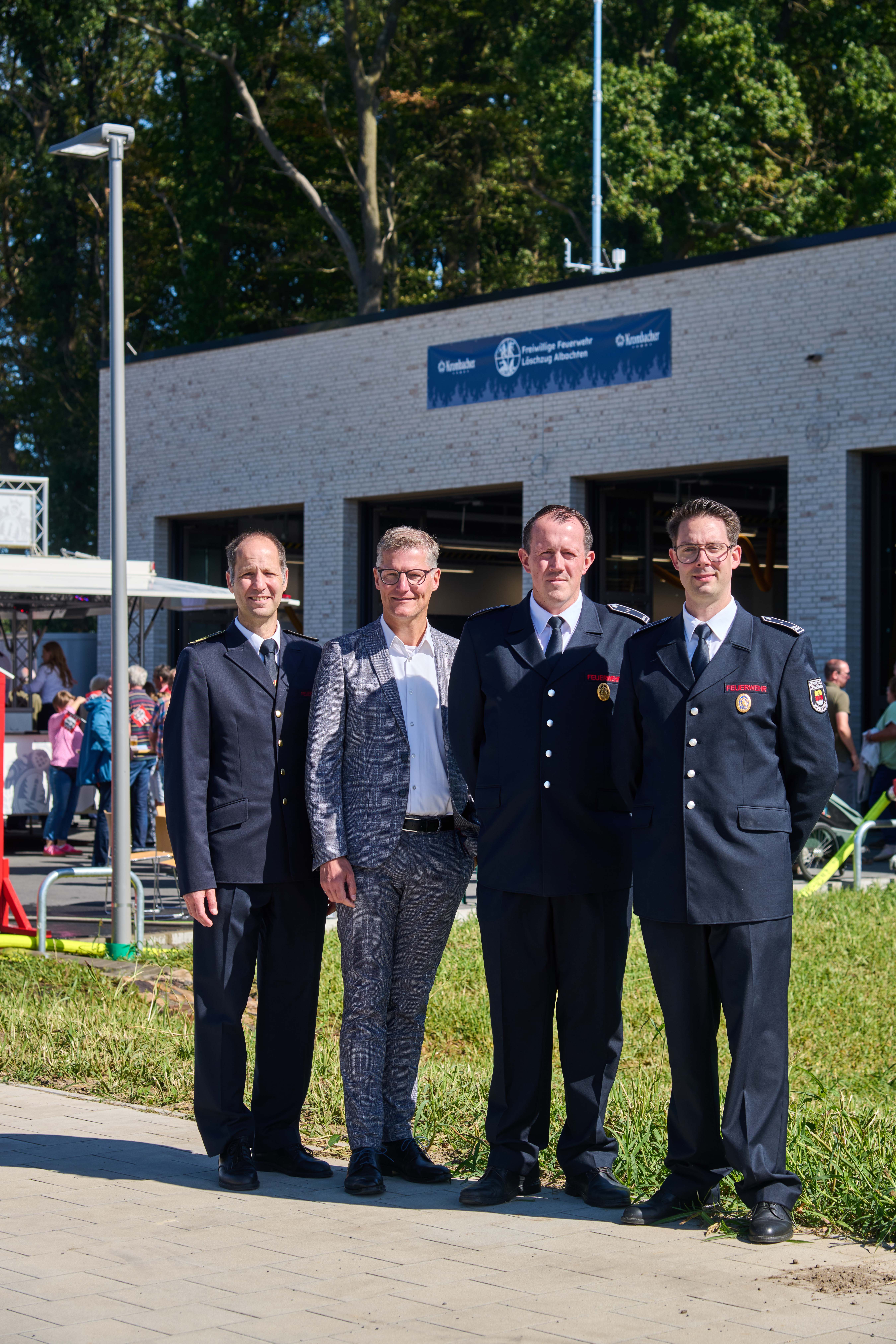 Vier Männer stehen vor dem neuen Feuerwehrhaus in Albachten