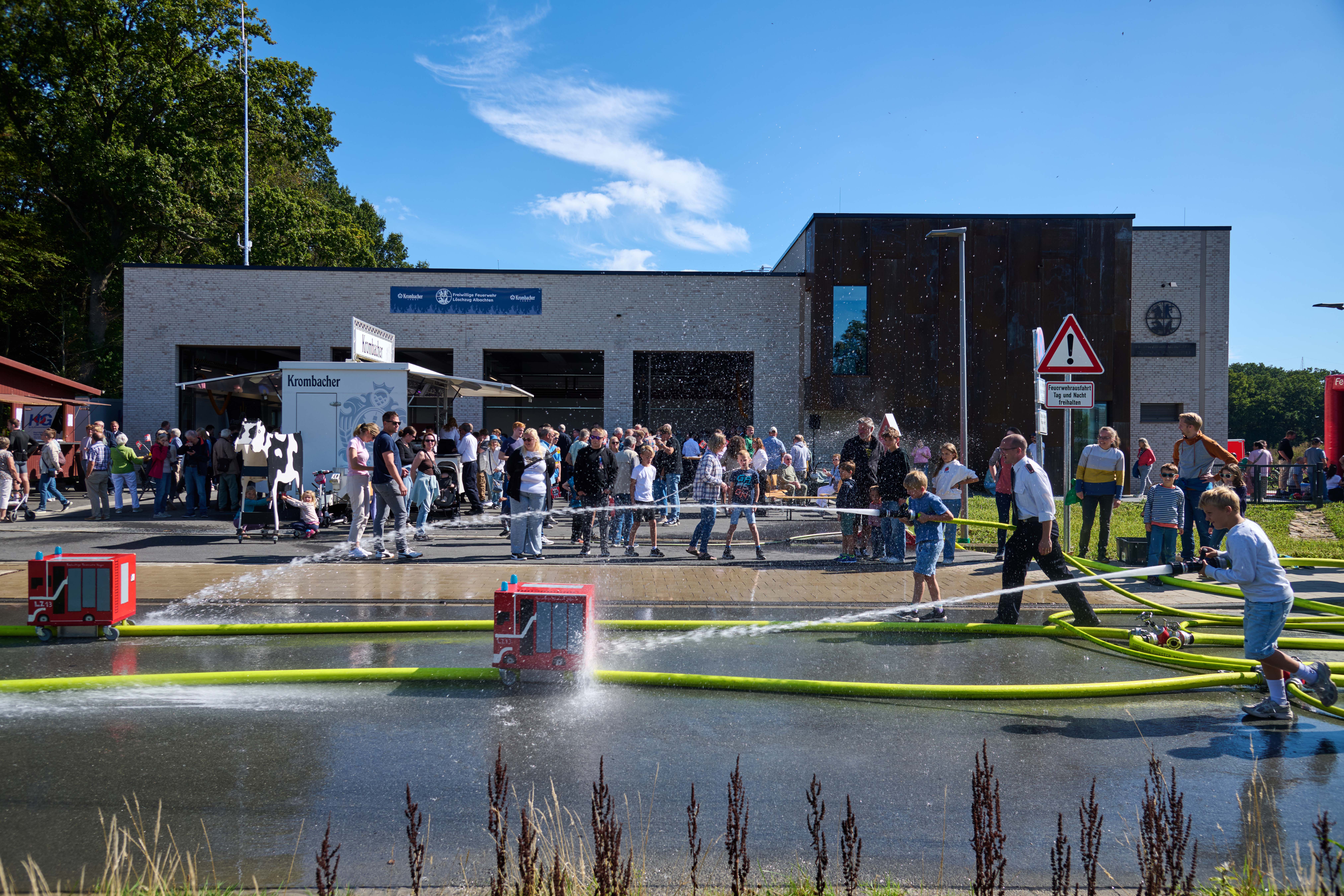 Viele Menschen mit Bierstand und Wasser-Mitmach-Spiel vor dem Feuerwehrhaus in Albachten.