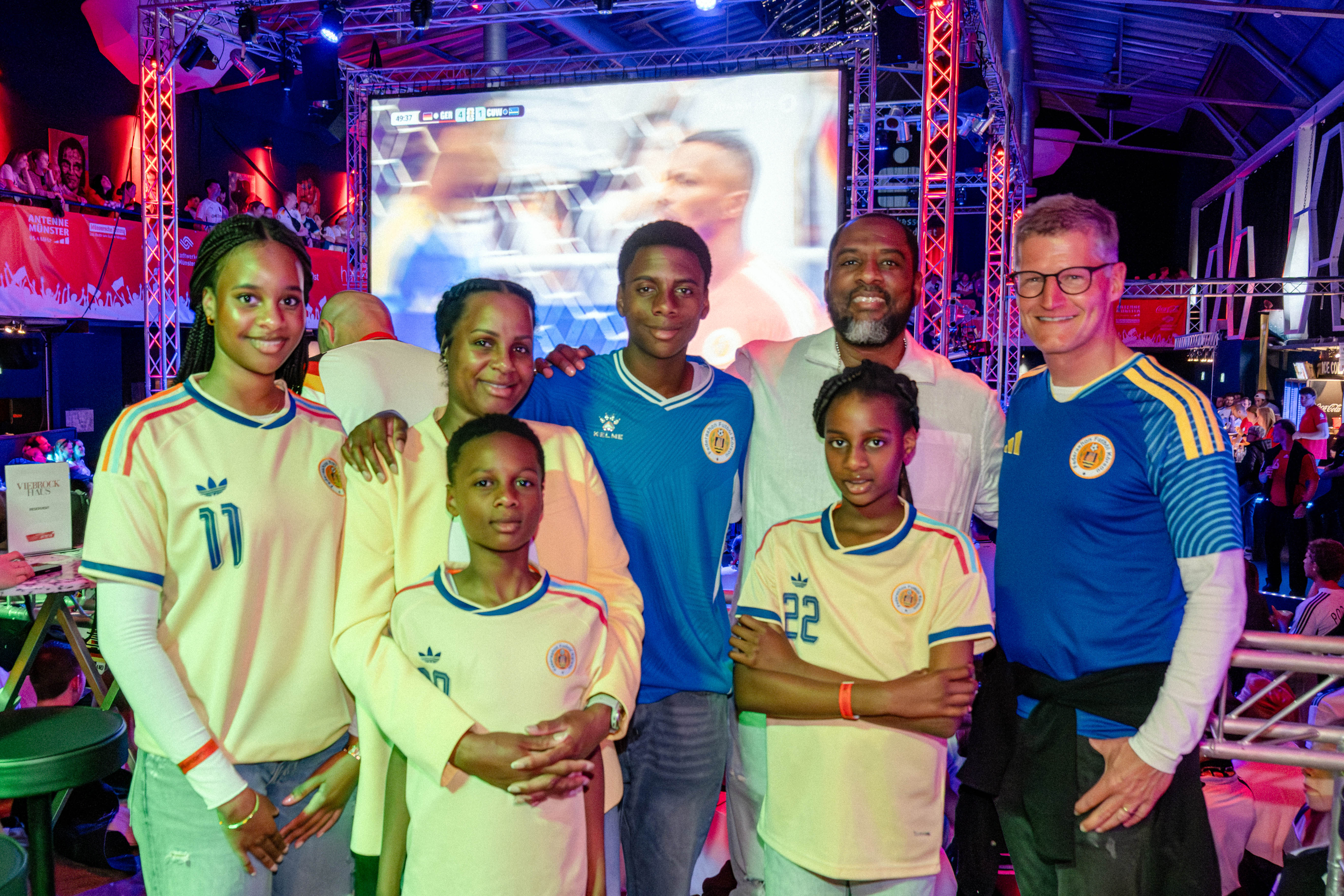 Personen in Fußballtrikots vor einer Leinwand