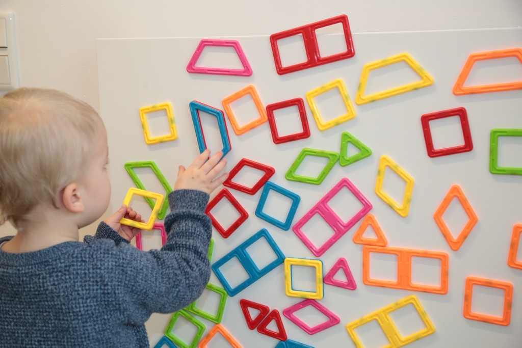 kleines Kind spielt mit bunten Magneten