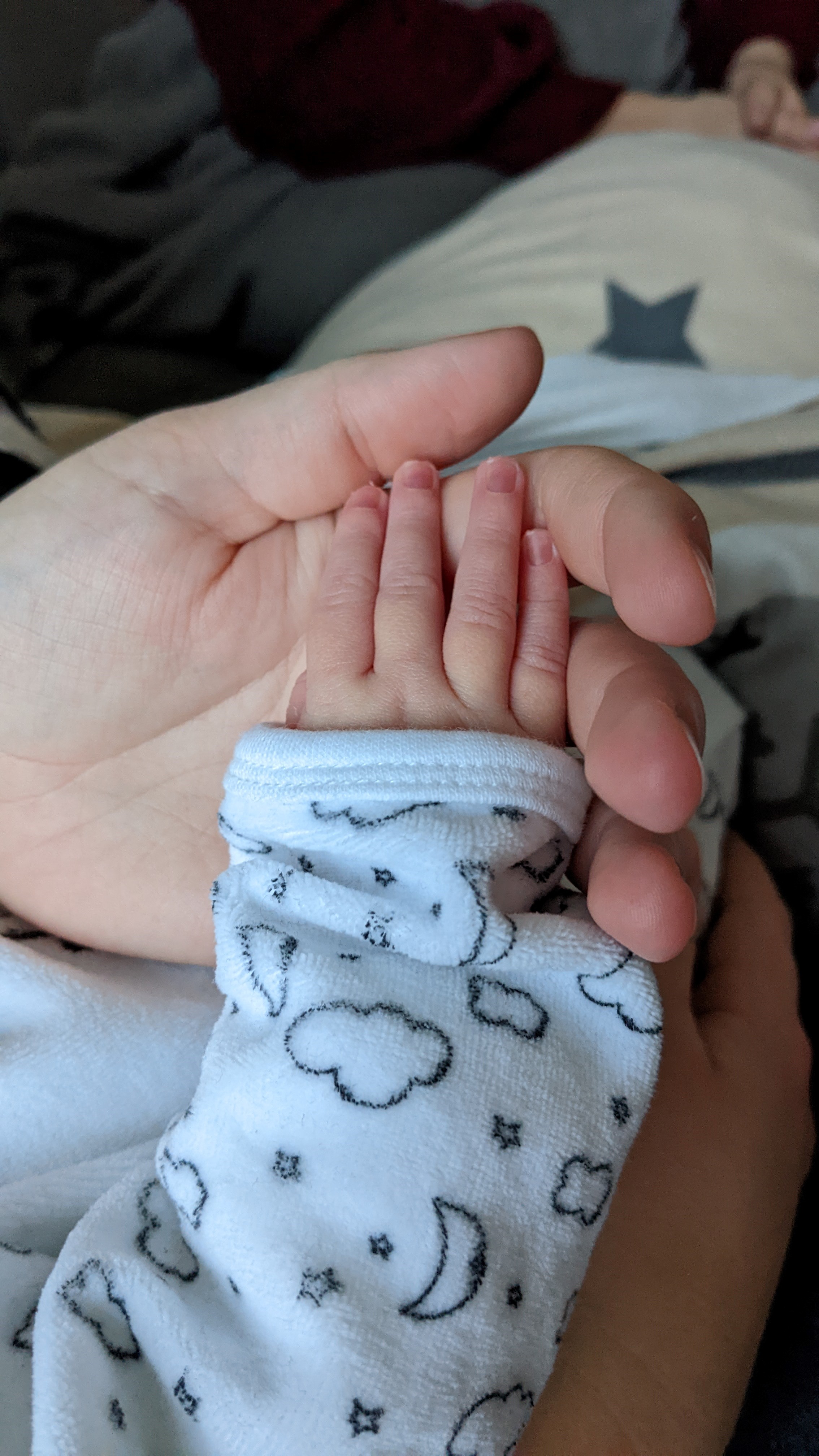 Hand eines Neugeborenen in der Hand eines Erwachsenen