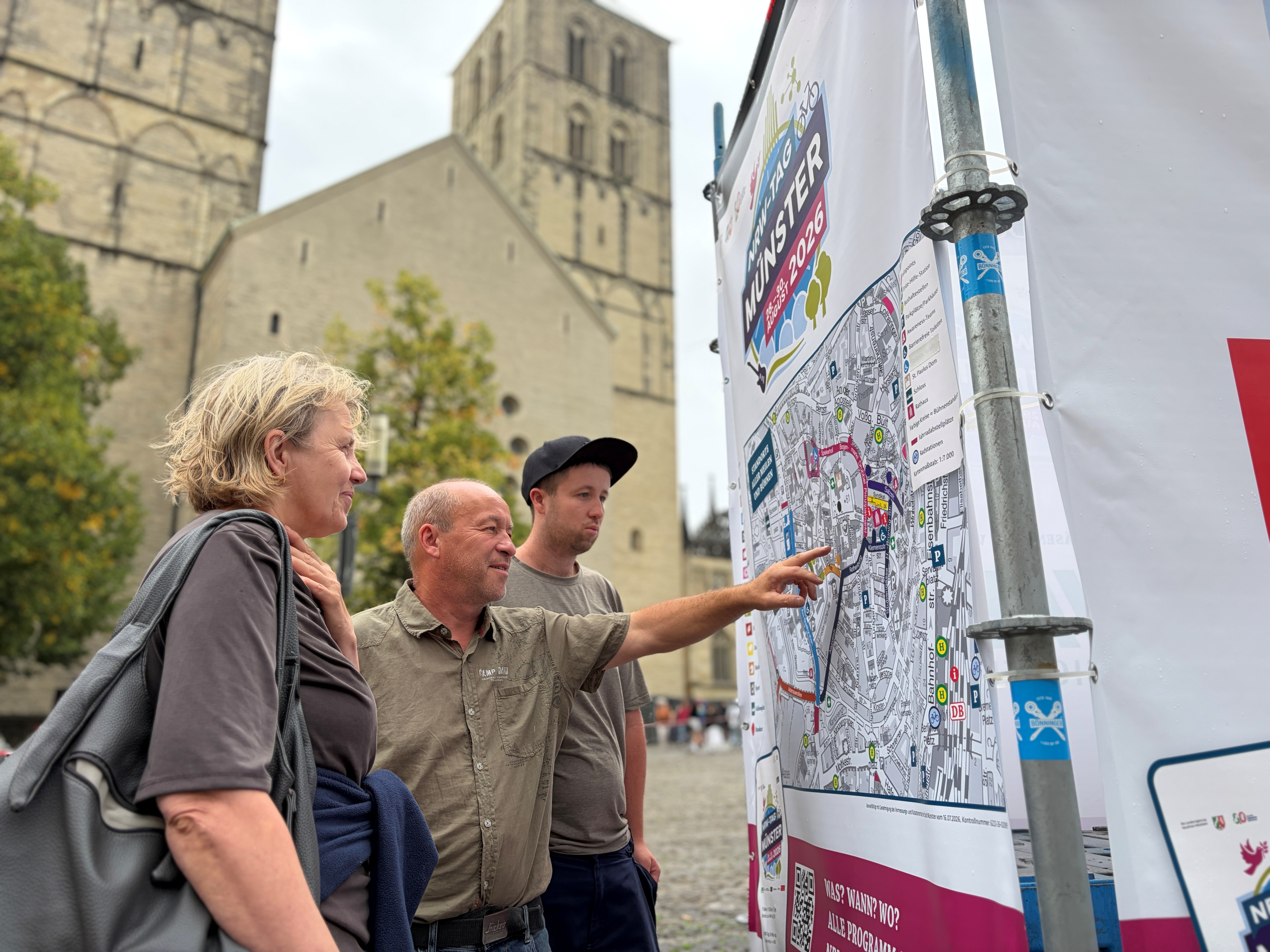 Besucher stehen an einer Übersichtskarte vor dem Dom