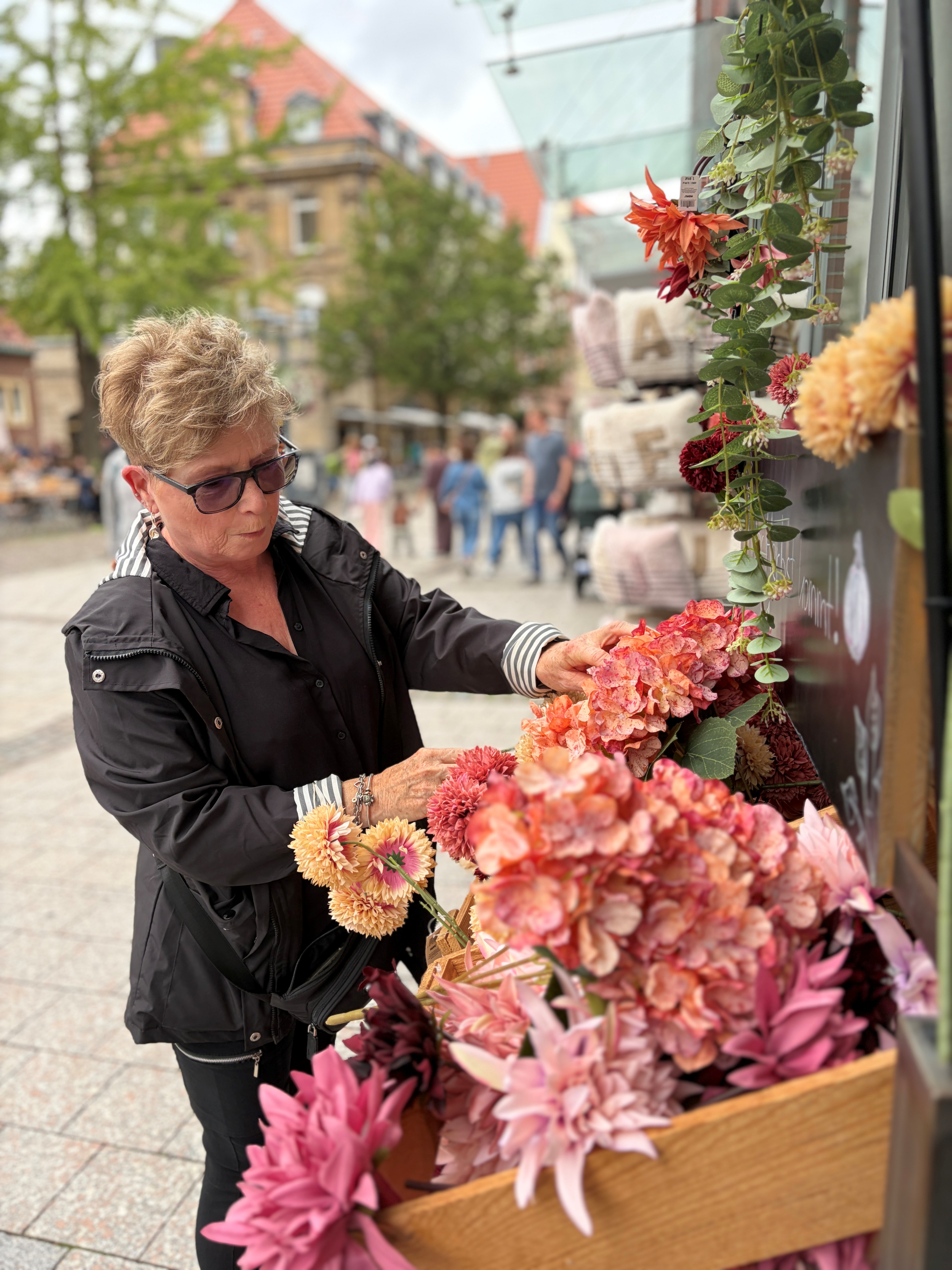 Eine Passantin stöbert im Blumensortiment in der Innenstadt.