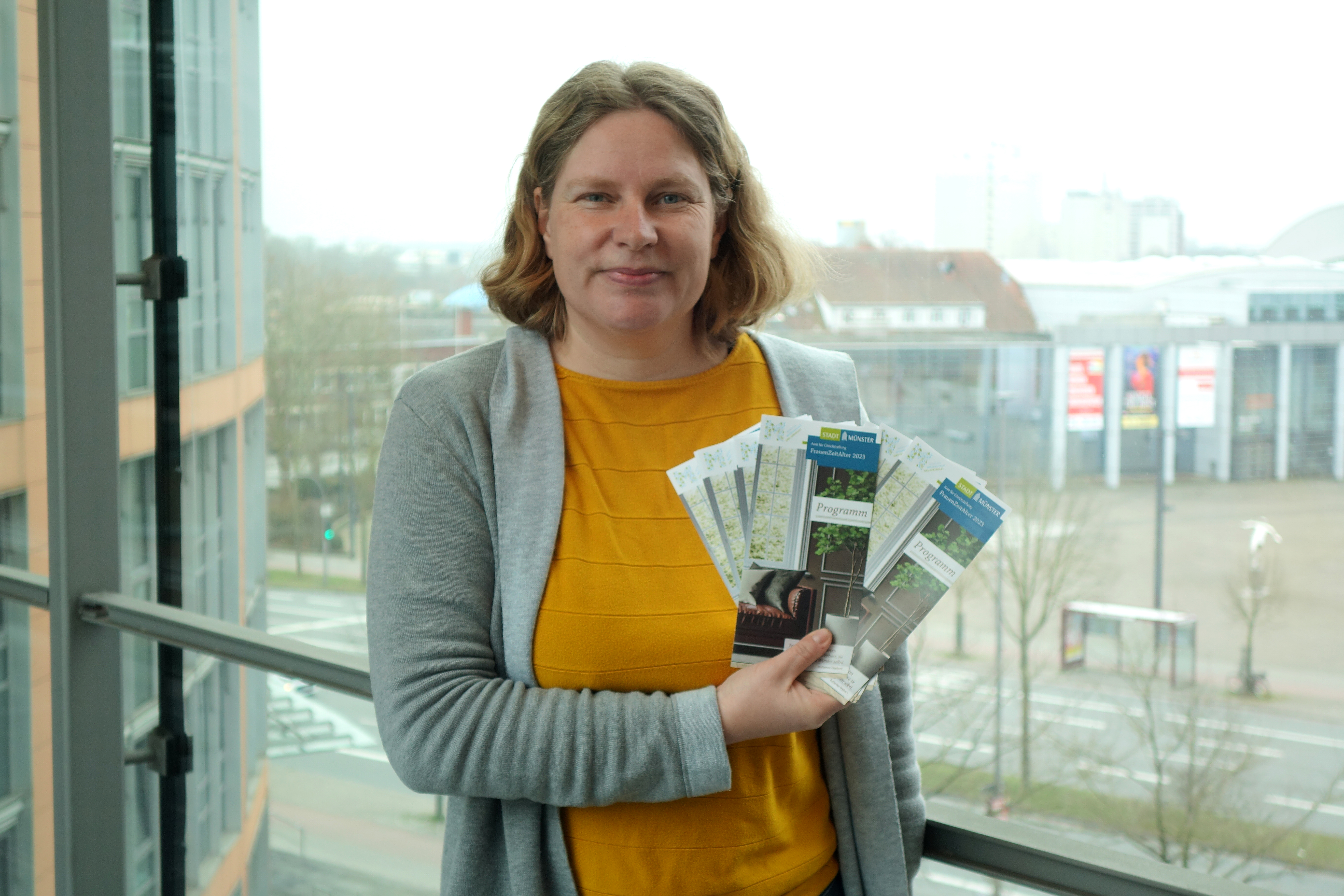 Sarah Braun, Leiterin des Amts für Gleichstellung der Stadt Münster, präsentiert den Flyer zum Jahresprogramm des Projektes „FrauenZeitAlter“ für 2023. 