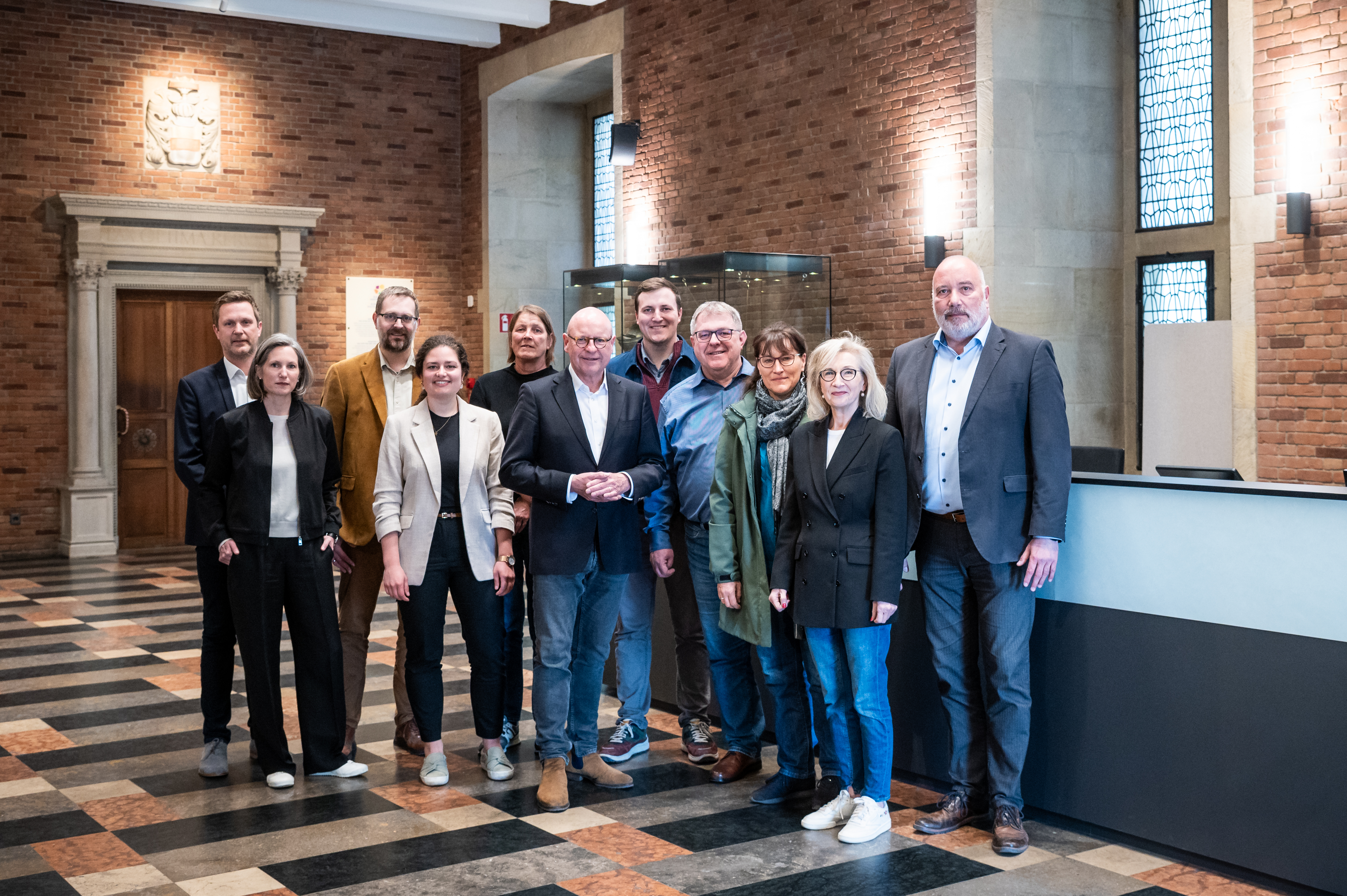 Oberbürgermeister Markus Lewe (6. v. l.), Immobiliendezernent Arno Minas (r.), Bernadette Spinnen (Leiterin Münster Marketing) (2. v. r.) freuen sich gemeinsam mit weiteren Projektbeteiligten aus Politik, Verwaltung und Architekturbüro über den abgeschlossenen Umbau der Bürgerhalle.