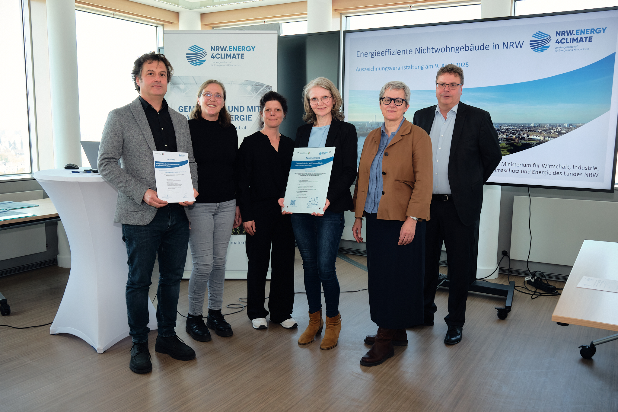 Freuen sich über die Auszeichnung für die Kita Hobbeltstraße (v. l.): Marc Dresen (Hansen + Partner Ingenieure), Maria Fischer, Susanne Hellmann und Michaela Selberg (alle Amt für Immobilienmanagement) sowie Silke Krebs (Staatssekretärin im Ministerium für Wirtschaft, Industrie, Klimaschutz und Energie des Landes NRW) und Carsten Petersdorff (Bereichsleiter Wärme & Gebäude NRW.Energy4Climate). 