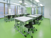 Fachraum: sechs Schreibtische mit Stühlen in einem Raum mit grünem Fußboden