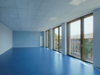 Leerer großer Raum mit bodentiefen Fenstern und blauem Fußboden