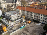 Eingerüstetes Gebäude, im Hintergrund ist eine Kirche zu sehen