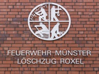 Fassade des Feuerwehrhauses - Detailaufnahme mit Feuerwehr-Emblem und Schriftzug 'FEUERWEHR MÜNSTER LÖSCHZUG ROXEL'