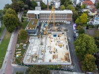 Schrägluftbild der Baustelle, dahinter das Bestandsgebäude