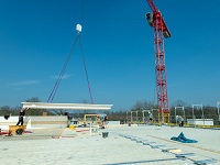 Foto Das 7 m lange Deckenelement schwebt per Kran ein und wird millimetergenau auf dem Dach des Haupthauses montiert.