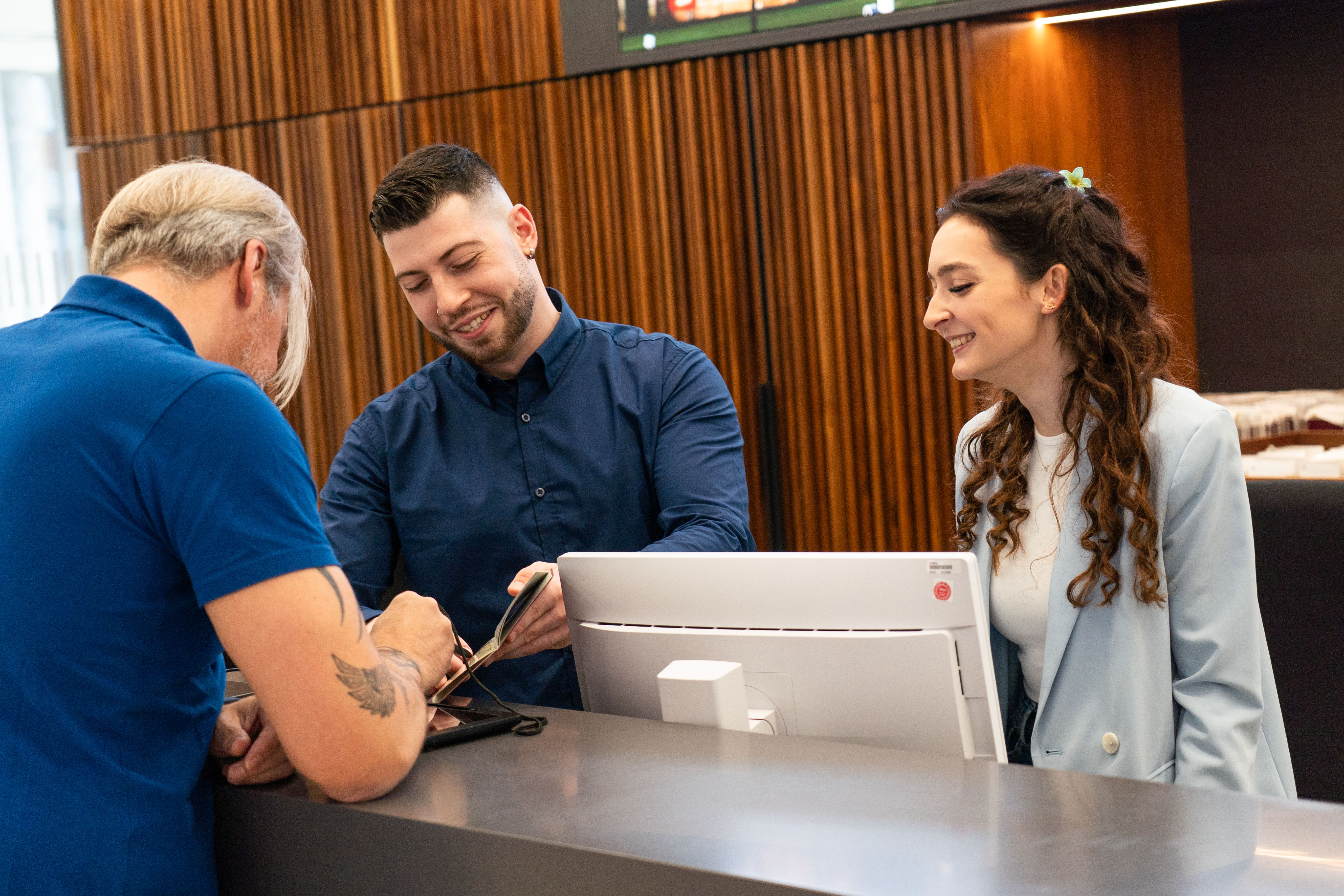 Zwei Personen stehen hinter einer Servicetheke und geben einem Mann vor der Theke Auskunft.