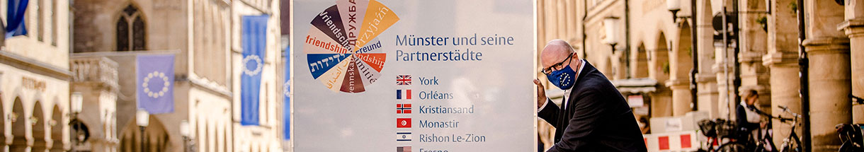 Oberbürgermeister Markus Lewe weist im Europa-Flaggenschmuck des Prinzipalmarktes auf die Partnerstädte, Münster