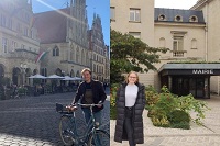 DFFD 2022/2023: ein junger Mann mit dem Fahrrad, das Münsters Rathaus im Hintergrund, eine junge Frau, die Orléans Stadtverwaltung im Hintergrund