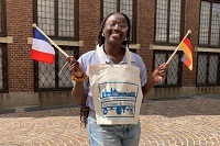 Eine junge Frau hält eine deutsche und eine französische Flagge in den Händen