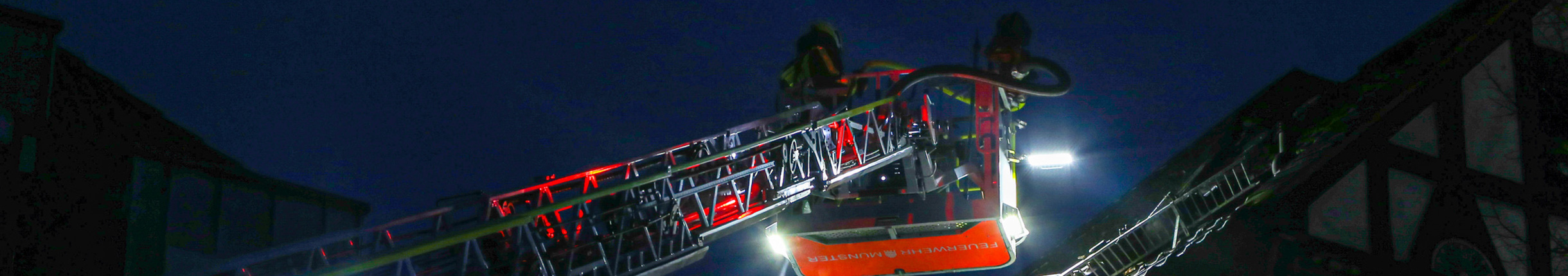 Zwei Feuerwehrleute im Korb auf dem Weg zum First eines Fachwerkhauses