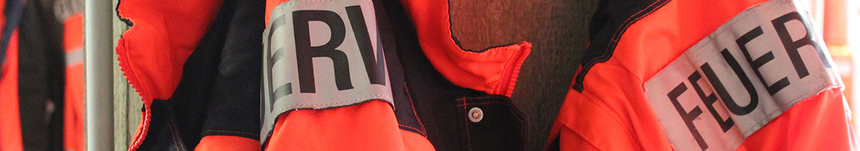 Orangefarbene Jacken mit Schriftzug 'Feuerwehr'