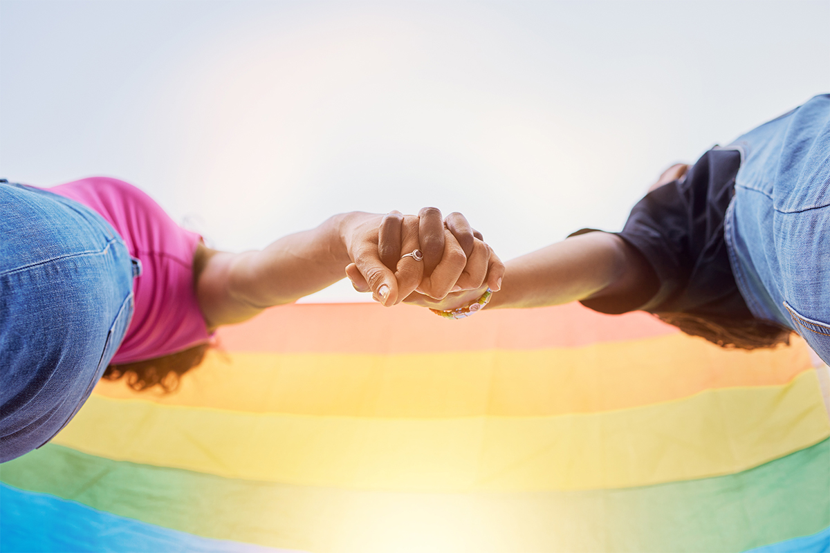 Zwei Junge Frauen halten sich an den Händen. Die Perspektive des Fotos ist stark untersichtig.