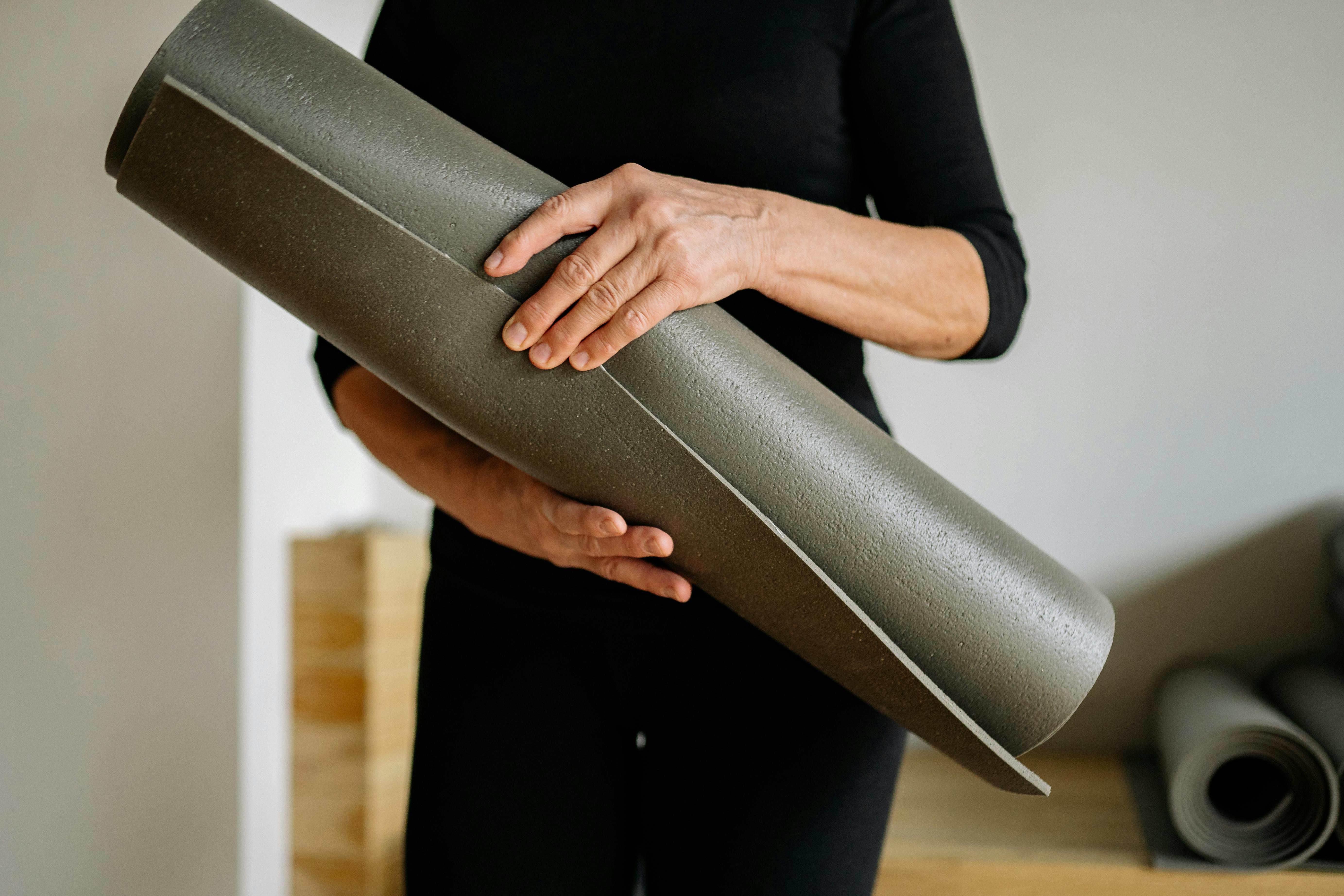 Junegr mann hält Yogamatte in den Händen