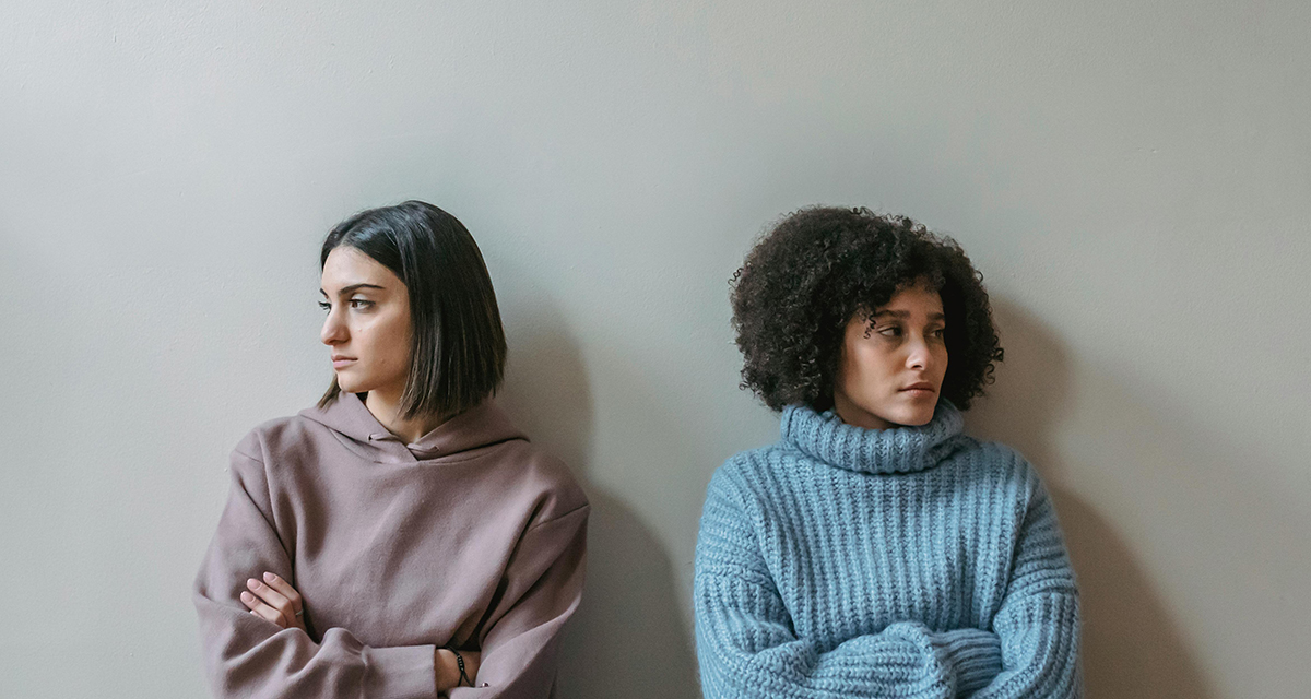 Zwei Frauen schweigen nach einem Streit und schauen voneinander weg.