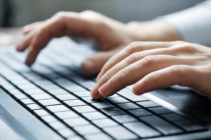 Zwei Hände, die auf einer unscharfen Tastatur tippen 