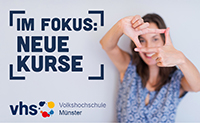 Eine Frau steht neben einem Plakat mit der Aufschrift 'Im Fokus: Neue Kurse'. Sie hält Daumen und Zeigefinder beider Hände zu einem Rechteck ausgestreckt vor ihr Gesicht.