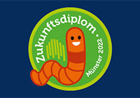 Signet zum Zukunftsdiplom 2022 Das Bild zeigt eine computeranmierte Zeichnung eines rot-braunen Wurms vor einem grünen Hintergrund. Dieser Wurm stellt das Maskottchen des Zukunftsdiploms 2022 dar.