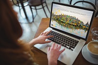 Abbildung zeigt einen Laptop auf einem Tisch und Hände, die auf ihm tippen.