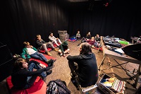 Eine Gruppe Menschen sitzt auf dem Boden und bespricht sich.