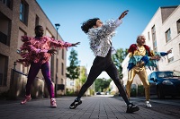 Abbildung von drei Performenden in Kostümen auf einer Straße