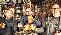 Bild des Trios mit ihren Instrumenten an einem Kneipentisch.
