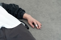 Still aus der Installation: Mensch liegt auf dem Boden 8angeschnitten) und hat ein Pflaster am Zeigefinger.