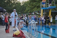 Freibad in Lienen. Ein Mann steht im Bademantel am Becken, ein anderer sitzt am Beckenrand und ist als Merrjungfrau verkleidet. (Foto: Florian Roy/RESET e.V.)