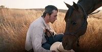 Filmstill zeigt einen Mann mit einem Pferd.