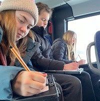 Jugendliche schreiben im öffentlichen Nahverkehr Texte.