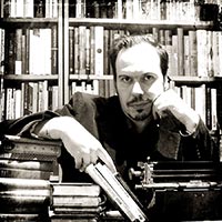 Porträtfoto von Matthias Engels an einer Schreibmaschine vor einem großen Bücherregal.