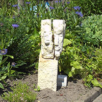 Skulptur: Stein-Figur mit einem kleinen und einem großen Gesicht