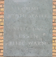 Steintafel mit der Inschrift: Komme heute später - Stell das Essen bitte warm