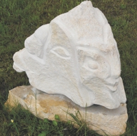 Grob gehauene Gesichter ine einem weißen Stein