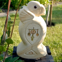 Sandsteinfigur eines stilisierten Falken mit farbigen Ornamenten auf der Brust