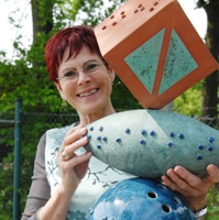 Künstlerin mit farbiger Keramikstele, die in Blindenschrift mit "Kunst trifft Kohl" beschriftet ist