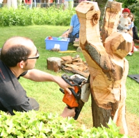 Der Künstler bearbeitet einen alten Baumstumpf mit einer Kettensäge zu einer Figur